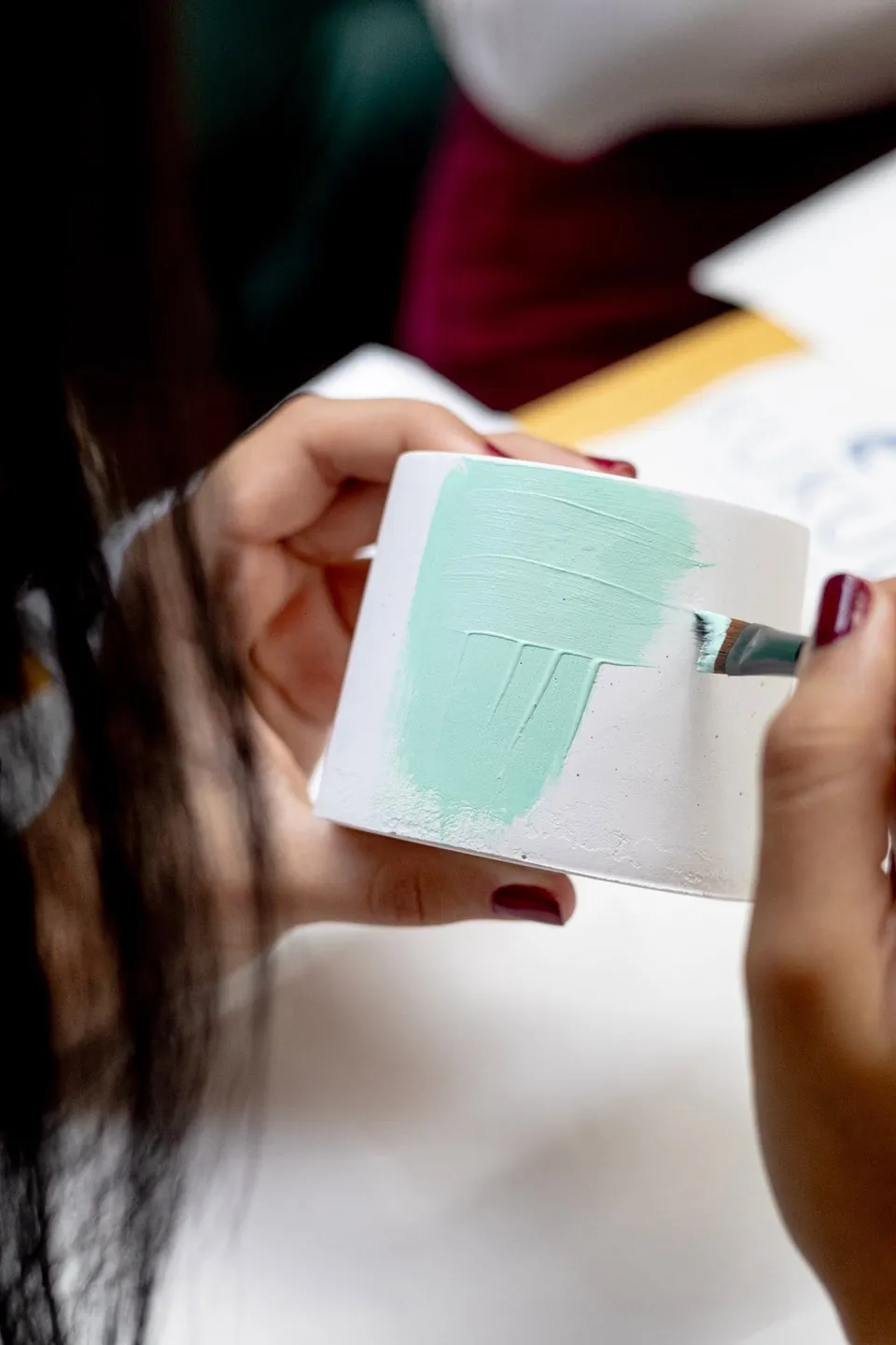Un pincel deja una pincelada verde menta sobre una taza blanca de cerámica